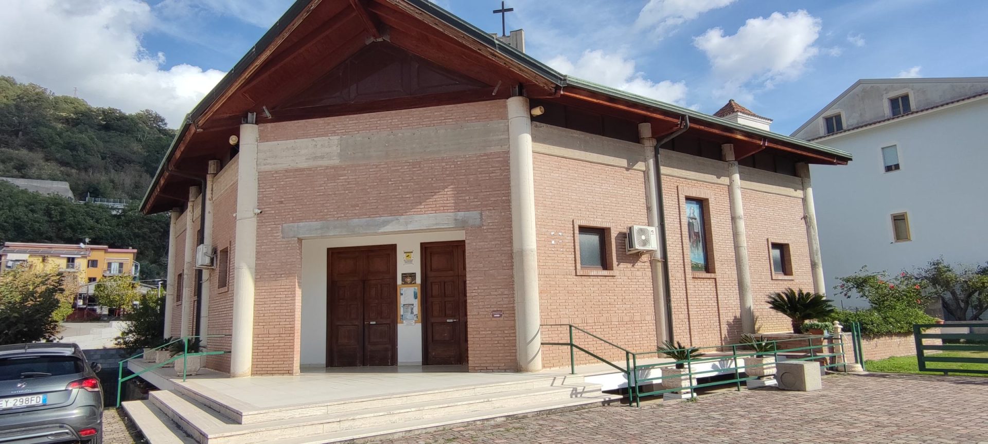 Le Chiese Facciata in mattoni a vista della Chiesa di Santa Maria Goretti, con il tetto a capanna in legno, la croce sul colmo e il sagrato in porfido, a Guardia Piemontese Marina