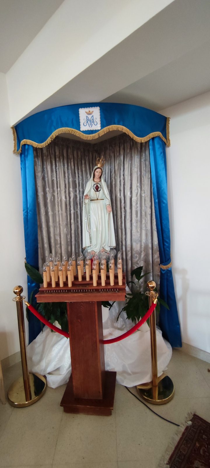 Chiesa Santa Maria Goretti Statua della Madonna di Fatima con il manto bianco e la corona, in una nicchia con i drappi azzurri e il candeliere votivo davanti, nella Chiesa di Santa Maria Goretti