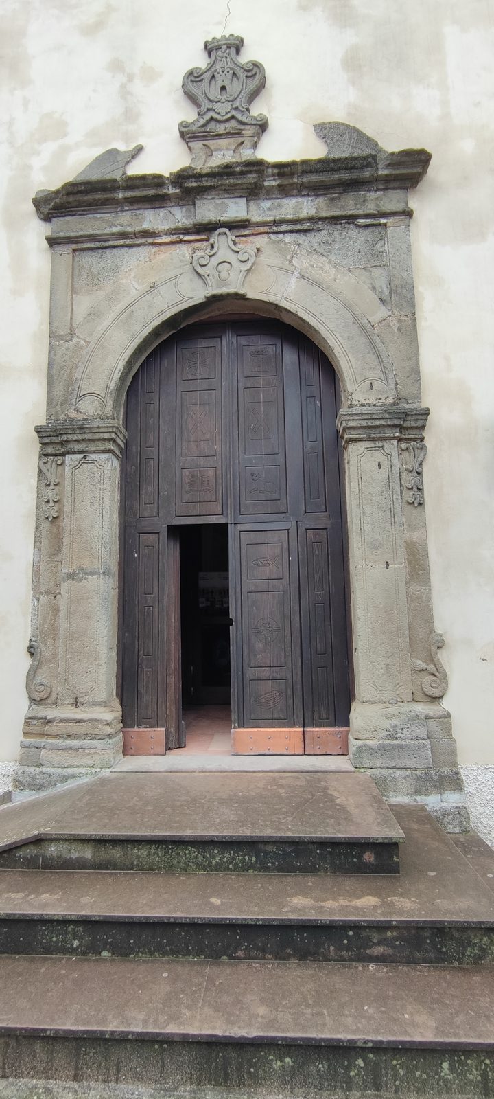 Chiesa Matrice — Sant'Andrea Apostolo Portale in pietra scolpita con arco a tutto sesto, stemma sul coronamento e battenti lignei socchiusi in cima alla gradinata, nella Chiesa Matrice di Sant'Andrea Apostolo