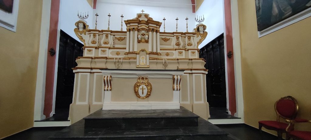 Altare maggiore barocco in stucco bianco e oro, con il tabernacolo al centro e la porta del coro alle spalle, nella Chiesa della Madonna SS. del Rosario