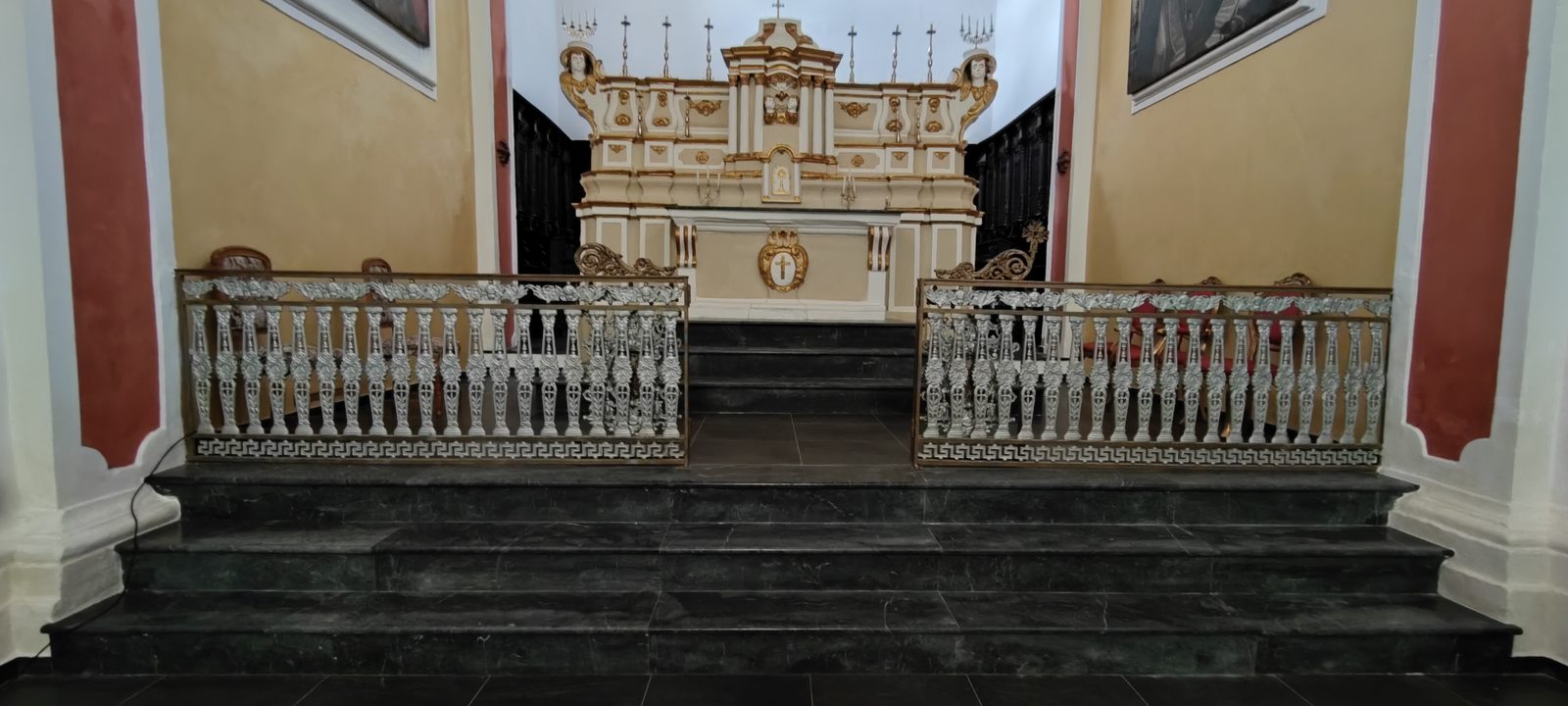 Chiesa Madonna SS. del Rosario Balaustra in metallo traforato davanti ai gradini in pietra scura del presbiterio, con l'altare maggiore barocco sullo sfondo, nella Chiesa della Madonna SS. del Rosario
