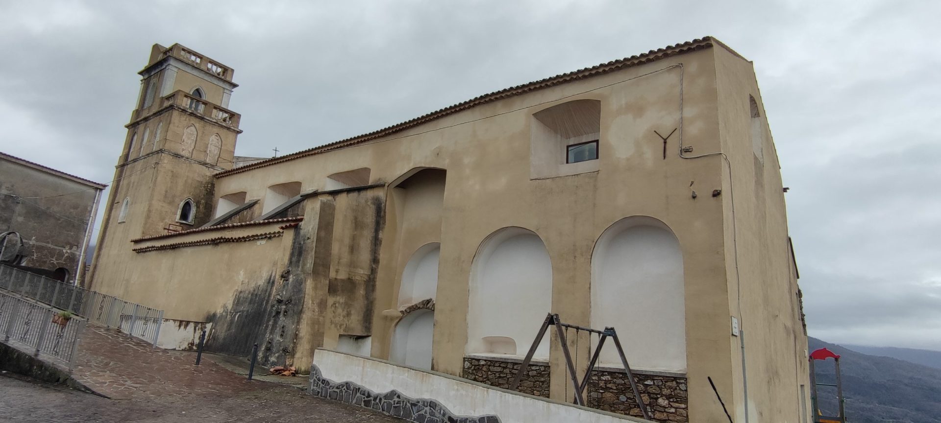Home Il fianco della Chiesa della Madonna SS. del Rosario con il campanile e le arcate cieche dell'ex convento domenicano, affacciato sul pendio di Guardia Piemontese