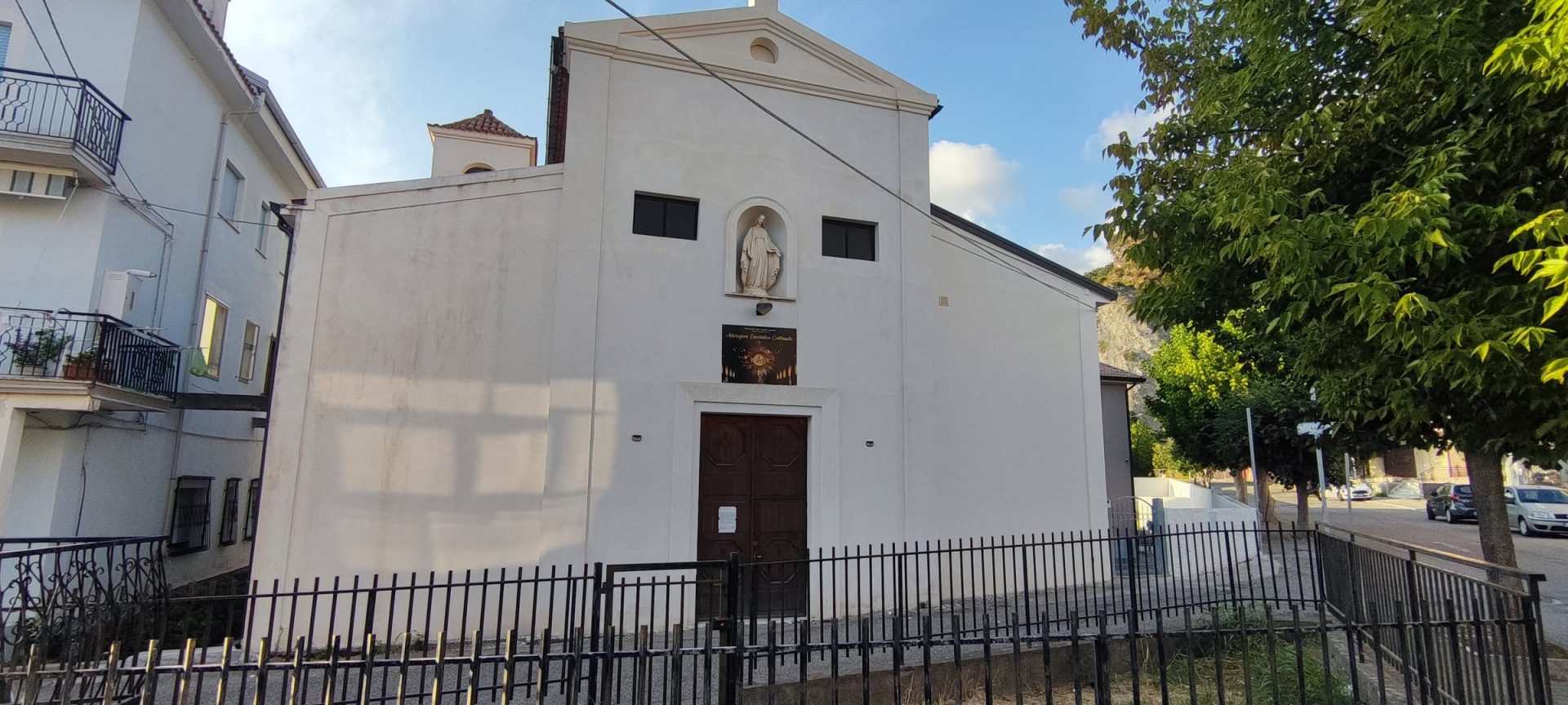 Le Chiese Facciata bianca a capanna della Chiesa del Santissimo Sacramento, con il timpano, la statua nella nicchia sopra il portale e la cancellata in ferro lungo il marciapiede